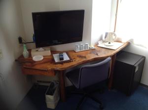 a desk with a television and a computer monitor on it at Asano Hotel in Kitakyushu