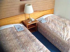 two beds in a room with a lamp on a night stand at Asano Hotel in Kitakyushu