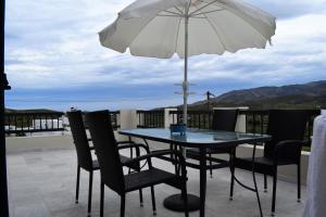 a table and chairs with an umbrella on a balcony at Daniel and Marina in Galini