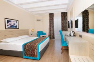 a hotel room with a bed and a desk and chairs at Kaila Beach Hotel - All Inclusive in Alanya