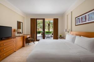 a bedroom with a bed and a television and a desk at Shangri-La Barr Al Jissah, Muscat in Muscat