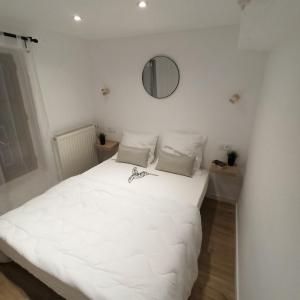 ein weißes Bett in einem weißen Zimmer mit einem Spiegel in der Unterkunft A 4 min du Zoo de Beauval La Maison à Partager Ch3 1er étage in Saint-Aignan