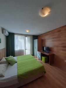 a bedroom with a large bed with a green blanket at Private Rooms Silvia in Varna City