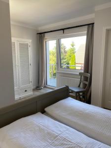 a bedroom with two beds and a large window at Hotel & Ferienunterkünfte Hus Seeblick in Fehmarn