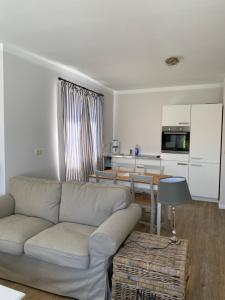 ein Wohnzimmer mit einem Sofa und einer Küche in der Unterkunft Hotel & Ferienunterkünfte Hus Seeblick in Fehmarn