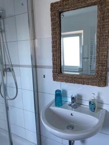 ein Bad mit einem Waschbecken und einem Spiegel in der Unterkunft Hotel & Ferienunterkünfte Hus Seeblick in Fehmarn