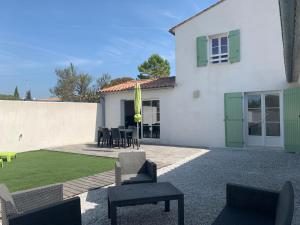 a house with a patio with chairs and a lawn at La Fleur de Sel in La Flotte
