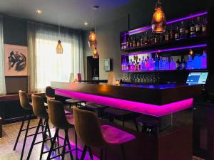 een bar met paarse verlichting in een kamer met krukken bij Hotel am Augustinerplatz in Keulen