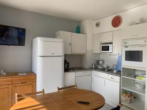 uma cozinha com uma mesa de madeira e electrodomésticos brancos em Appartement T2 cabine, capacité 4 personnes, à 600 m de la plage et à 300 m du Golf em Moliets-et-Maa