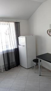 eine Küche mit einem Kühlschrank, einem Tisch und einem Fenster in der Unterkunft Apartament Buk in Riwne