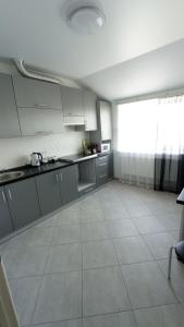 een keuken met witte kasten en een tegelvloer bij Apartament Buk in Rivne