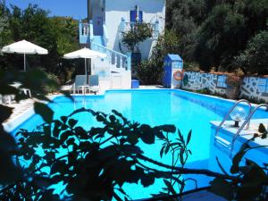 a blue swimming pool with chairs and umbrellas at Meltemia Studios in Marathokampos