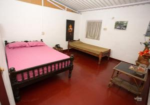 a bedroom with a pink bed and a table at Moonlight Munnar Forest Bungalow with Private Waterfalls by VOYE HOMES in Kanthalloor