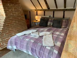 a bed in a room with a brick wall at Myrtle cottage in Dickleburgh