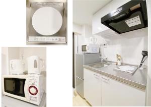 Biała kuchnia z kuchenką mikrofalową i zlewem w obiekcie nestay apartment tokyo nippori w Tokio