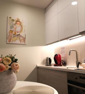 una cocina con armarios blancos y un jarrón de flores en Apartment by the Linden trees en Vilna