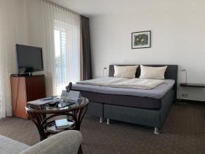 een slaapkamer met een bed en een televisie en een tafel bij Hotel Buntrock in Holzminden