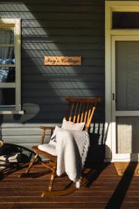 a wooden rocking chair on the porch of a house at Fay's Cottage in Dorrigo