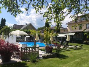 einen Pool im Garten mit Stühlen und Sonnenschirmen in der Unterkunft Ferienanlage Seehof in Krumpendorf am Wörthersee