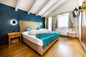 1 dormitorio con 1 cama con pared azul en Ciasa Milandura, en San Cassiano