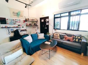 uma sala de estar com um sofá azul e uma mesa em 都蘭朋友家 Dulan Friends Hostel em Donghe