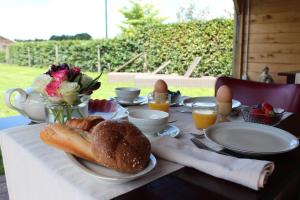 a table with a breakfast of bread and eggs and flowers at B&B 't Mjeels Pierke in Meerle