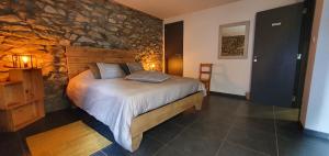 um quarto com uma cama com uma parede de pedra em O Près de la Lienne, maison de campagne de charme, accord parfait entre confort et authenticité em Lierneux