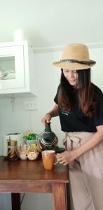 a woman in a hat is stirring a pot on a table at Rai Lung Tui Homestay in Prachuap Khiri Khan