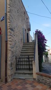 a stone building with a gate next to a staircase at Appartement duplex in Le Boulou