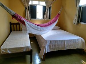 een hangmat tussen twee bedden in een kamer bij Pousada Formosa Baia in Baía Formosa