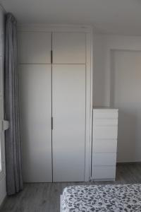 a white bedroom with a bed and a dresser at Apartamento Playa vistas 2 in Los Cristianos