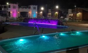 a swimming pool with a water fountain at night at Complejo Enjoy da Barra in Chuí