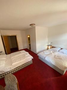 zwei Betten in einem Hotelzimmer mit rotem Teppich in der Unterkunft Märkischer Hof Hotel in Berlin