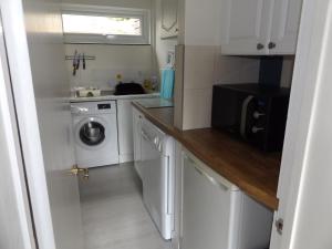 a small white kitchen with a washer and dryer at Family guest suite in Cheselbourne in Dorchester