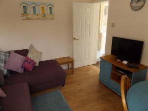 ein Wohnzimmer mit einem Sofa und einem Flachbild-TV in der Unterkunft Family guest suite in Cheselbourne in Dorchester