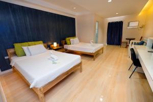 a hotel room with two beds and a desk at Pescadores Suites Moalboal in Moalboal