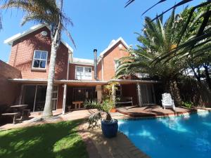 a house with a swimming pool and palm trees at Elements Cape Town in Table View