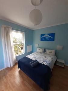 Dormitorio azul con cama y ventana en Elements Cape Town, en Table View