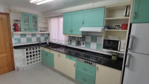 uma cozinha com armários verdes e brancos e um frigorífico em Ca la Glori em Los Corrales