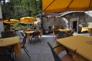 un patio con mesas, sillas y sombrillas amarillas en Hotel Al Forte, en Arabba