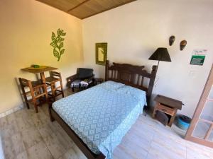 a bedroom with a bed and a table and a chair at Toca dos Pássaros in Boicucanga
