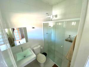 a bathroom with a toilet and a glass shower at Toca dos Pássaros in Boicucanga +49 photos