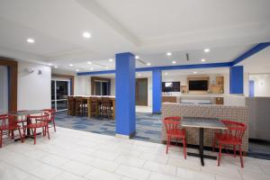 a restaurant with red chairs and tables and a kitchen at Holiday Inn Express Slidell, an IHG Hotel in Slidell