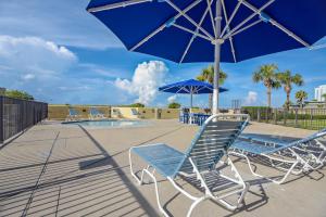 een groep stoelen en een parasol naast een zwembad bij Phoenix 6 Unit 504 in Orange Beach