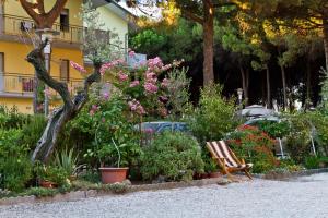 a bench in a garden with flowers and plants at Villa dei Fiori Apartments in Cervia