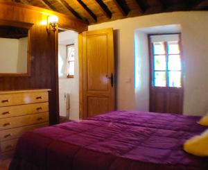 a bedroom with a purple bed with a dresser and a door at La casa de La Cartita in Puntagorda