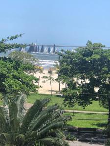 a view of a beach with a bridge in the background at Apto Gonzaga Frente ao Mar Wi-Fi in Santos