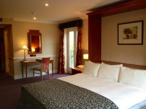 a hotel room with a large bed and a table at Quorn Country Hotel in Loughborough