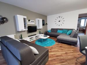 una sala de estar con 2 sofás y un reloj en la pared en Freedom Apartman en Hajdúszoboszló