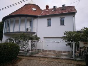 une maison blanche avec une clôture devant elle dans l'établissement Kupola Apartman, à Szeged